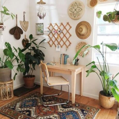 פינת משרד ביתי של בוהו עם שולחן לבן קליט, כסא ראטאן, מקרמה, צמחים פנימיים גדולים.