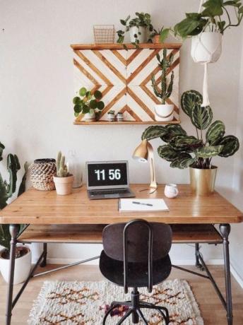 משרד ביתי נפלא בסגנון בוהו עם שולחן עץ רטרו ושטיח בוהו.