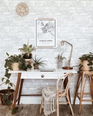 משרד ביתי בוהו שיק עם שולחן מעץ רטרו, שטיח בוהו, מלאכת קיר, המון צמחי בית: קקטוסים ועסיסי בשרניים